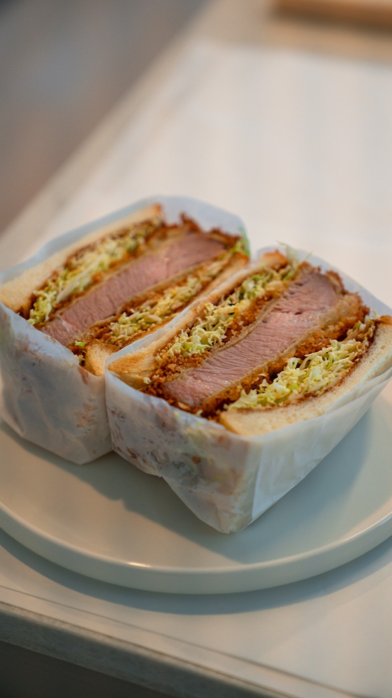 Kari Kari Sando katsu sando cut in half on a plate, showing the pink pork cross-section and lacy panko crust